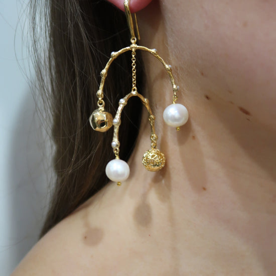 Gold earrings with pearl-like beads worn by a person
