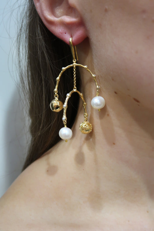 Gold earrings with pearl-like beads worn by a person