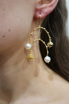 Gold and pearl earring worn on an ear
