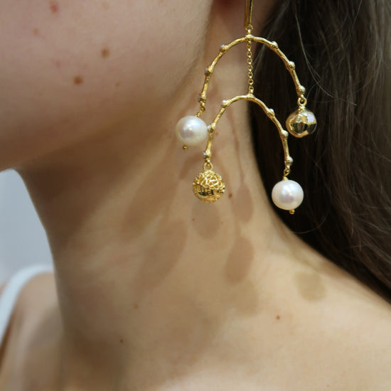 Gold and pearl earring worn by a person