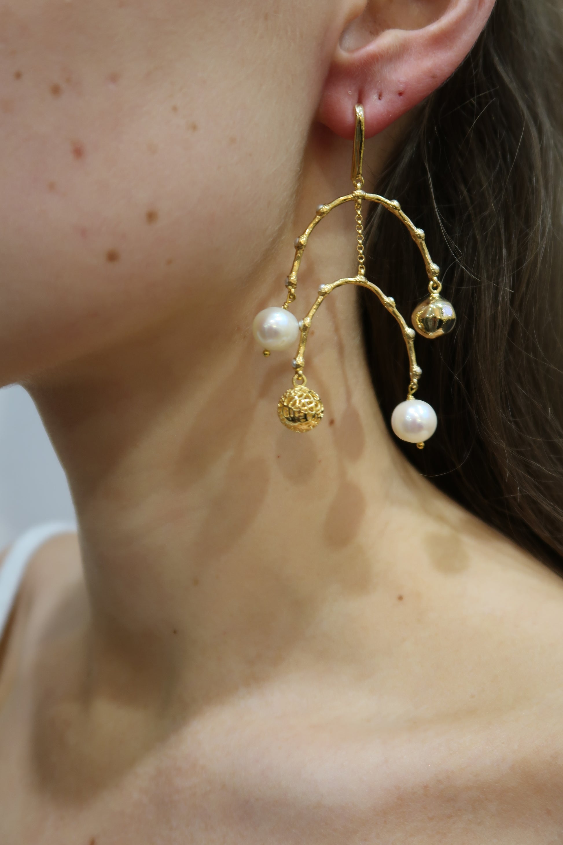 Gold and pearl earring worn by a person