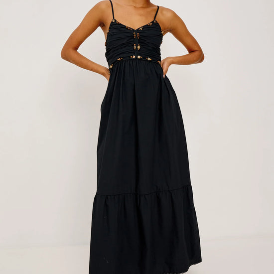 Woman wearing a black dress with gold accents on a white background