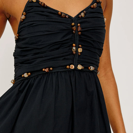Black dress with gold buttons on a plain background