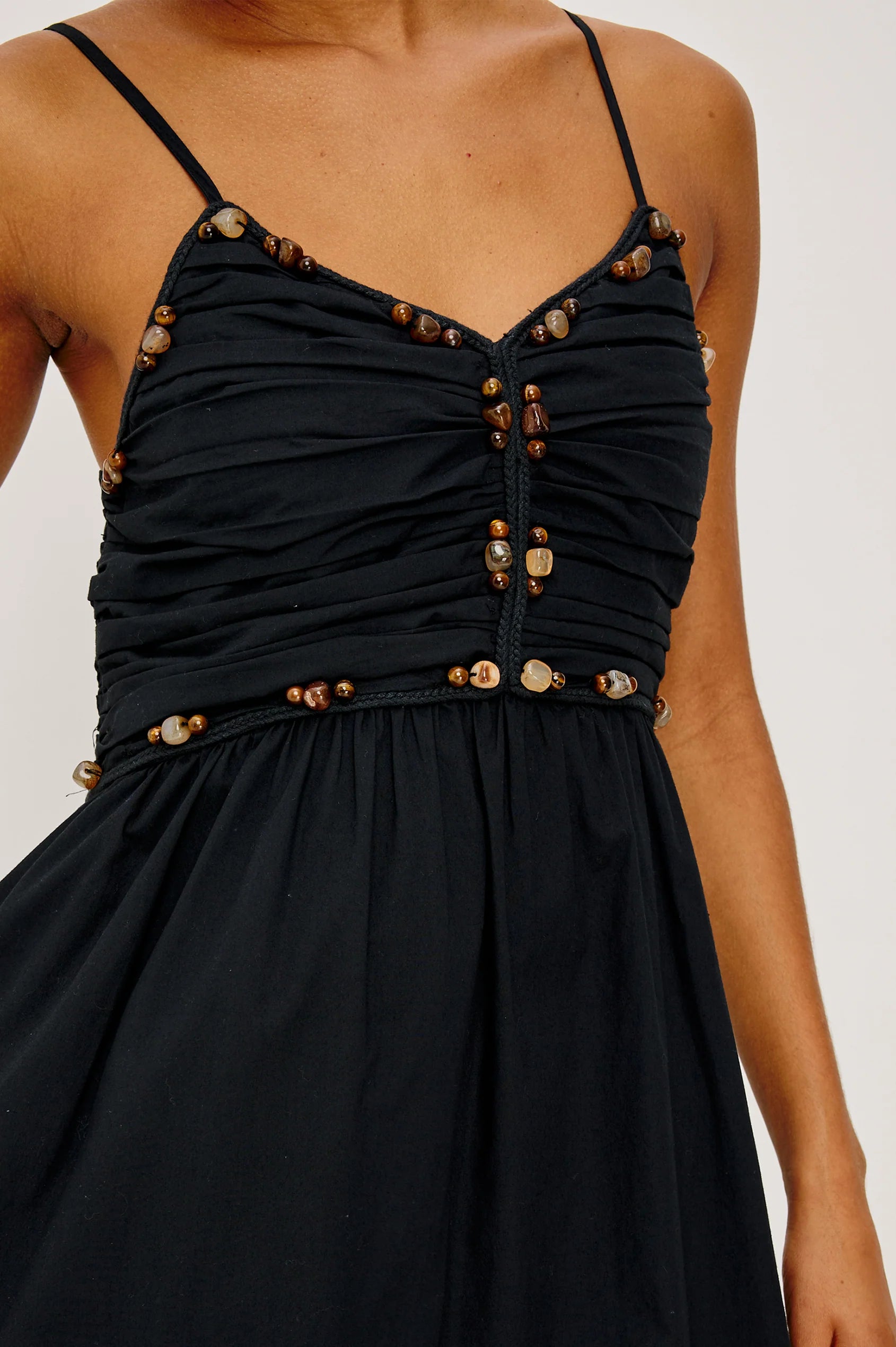 Black dress with gold buttons on a plain background