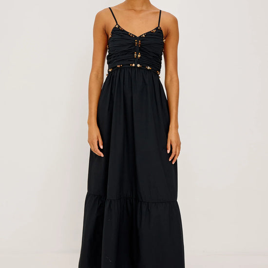 Woman wearing a black dress with gold accents on a white background
