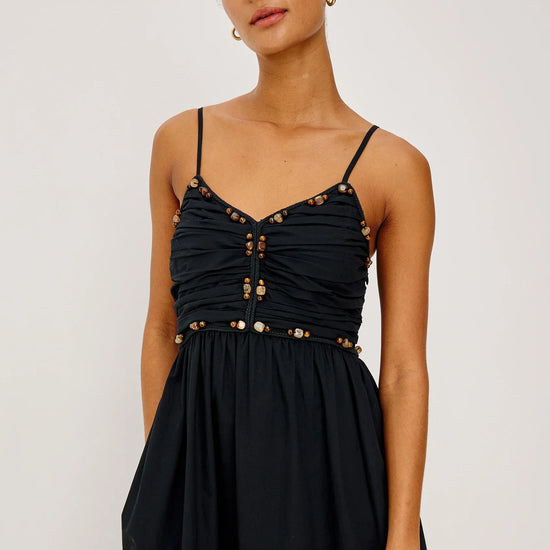 Woman wearing a black dress with gold buttons on a white background