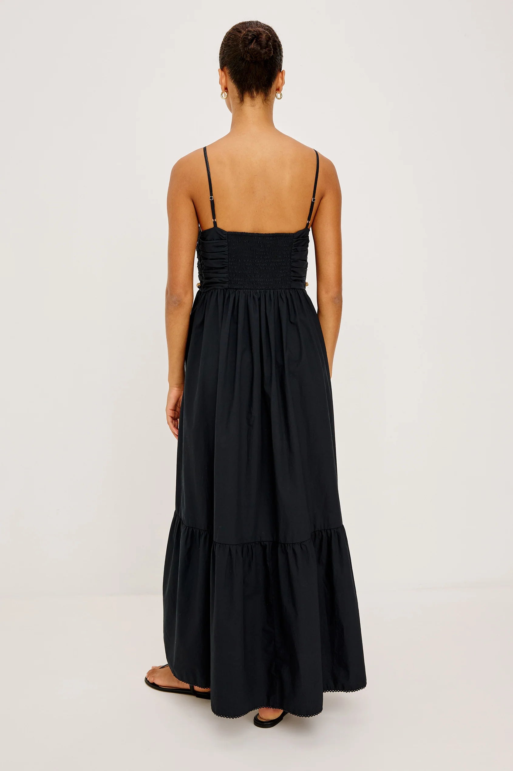 Woman wearing a black dress with thin straps on a white background