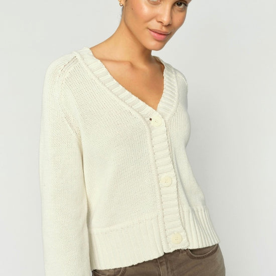 Woman wearing a cream cardigan against a plain background