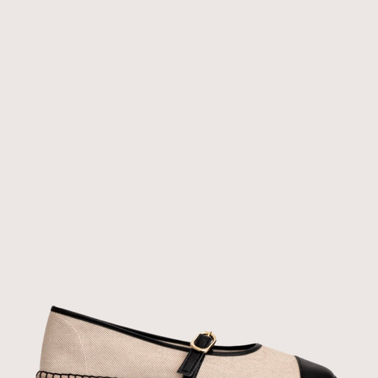 Beige flat shoe with black cap-toe and woven sole 