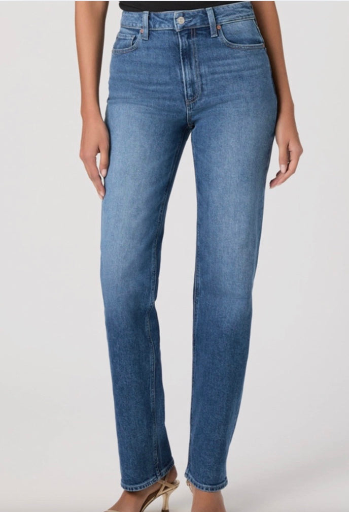 Person wearing blue jeans and a black top on a white background