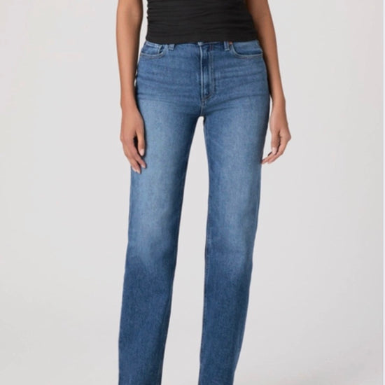 Person wearing blue jeans and a black top on a white background