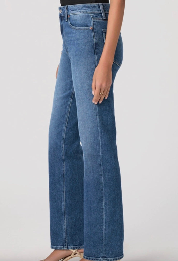 Person wearing blue jeans and a black top on a white background