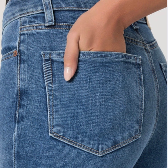 Person wearing blue jeans and a black top on a white background