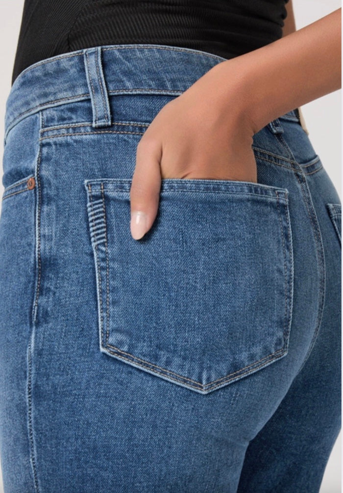 Person wearing blue jeans and a black top on a white background