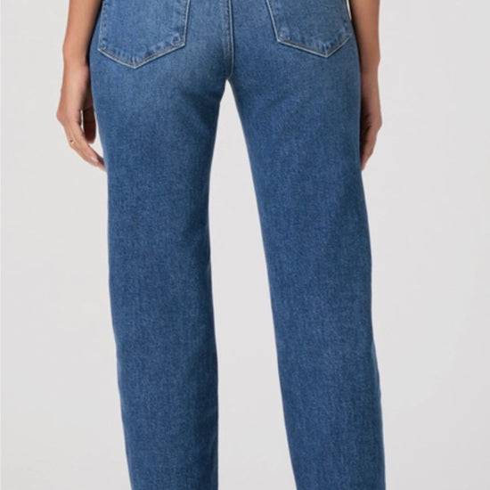 Person wearing blue jeans and a black top on a white background