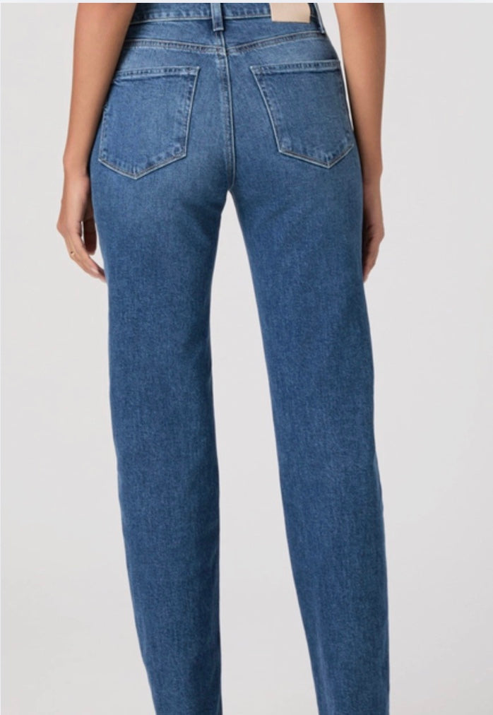 Person wearing blue jeans and a black top on a white background