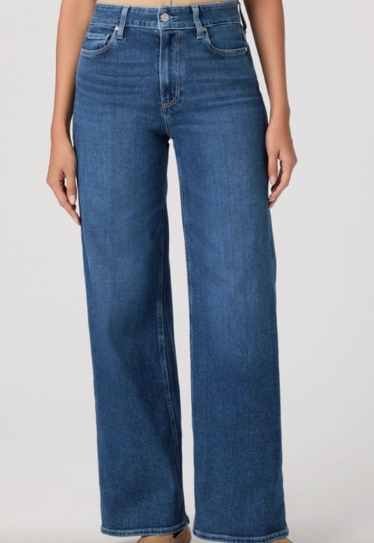 Person wearing a beige cardigan, beige top, and blue jeans on a white background