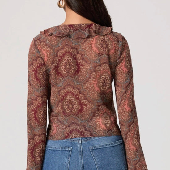 Woman wearing a patterned blouse and blue jeans on a white background