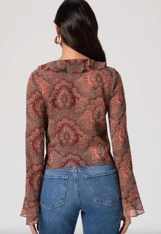 Woman wearing a patterned blouse and blue jeans on a white background