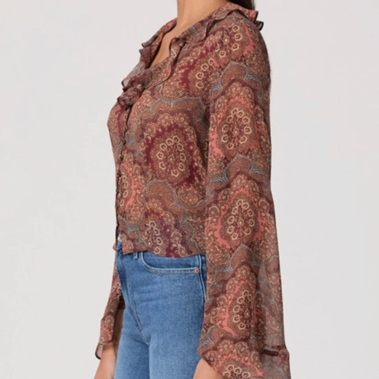 Woman wearing a patterned blouse and blue jeans on a white background