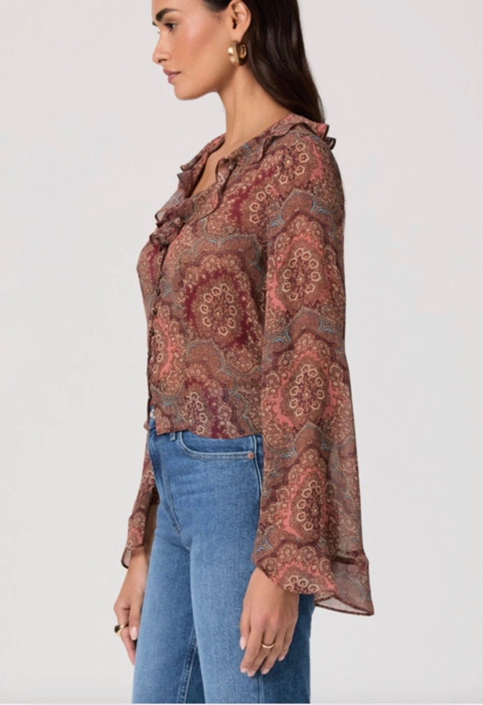 Woman wearing a patterned blouse and blue jeans on a white background