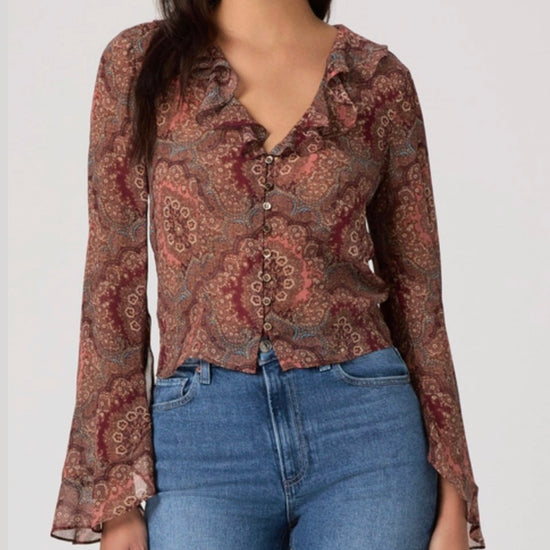 Woman wearing a patterned blouse and blue jeans on a white background