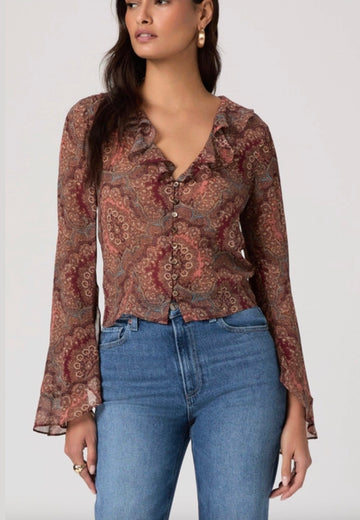 Woman wearing a patterned blouse and blue jeans on a white background