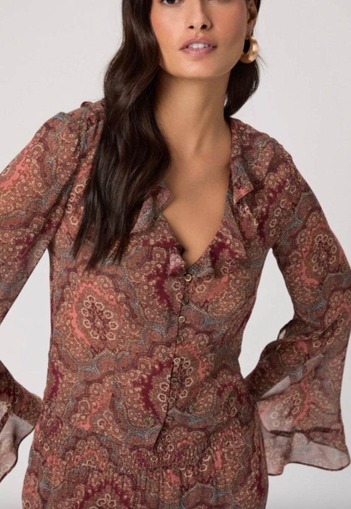 Woman wearing a patterned blouse and blue jeans on a white background