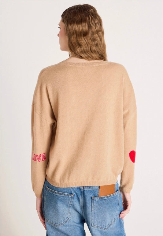 Woman wearing a beige sweater with text and blue jeans on a white background
