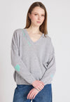 Woman wearing a gray sweater with heart patterns on a plain background