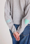Woman wearing a gray sweater with heart patterns on a plain background