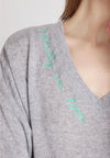 Woman wearing a gray sweater with heart patterns on a plain background