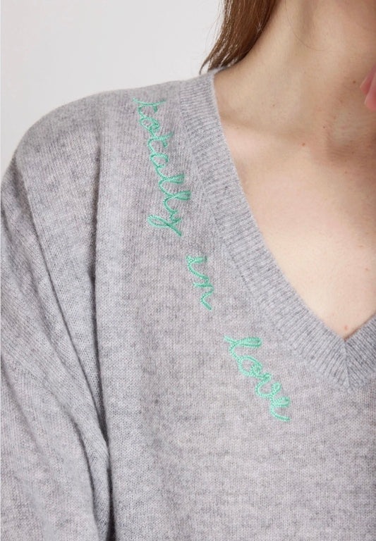 Woman wearing a gray sweater with heart patterns on a plain background