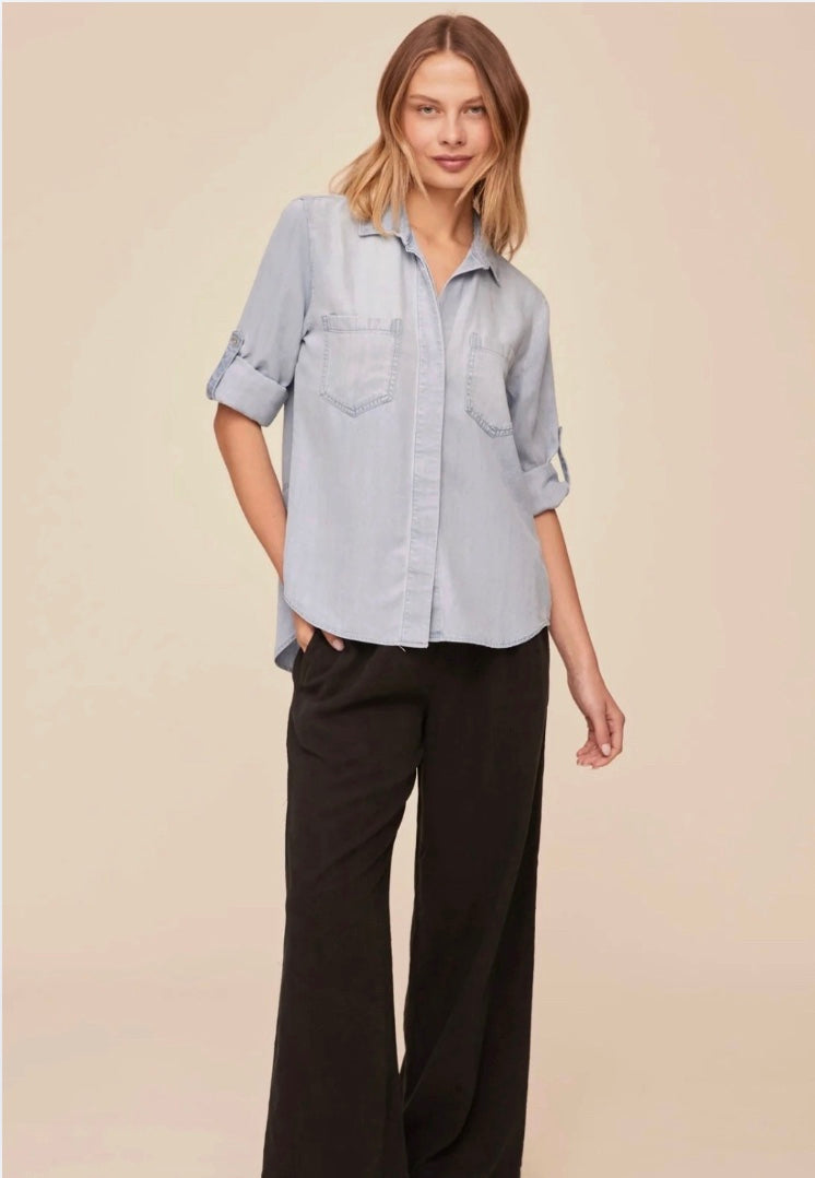 Woman wearing a light blue shirt and black pants on a beige background