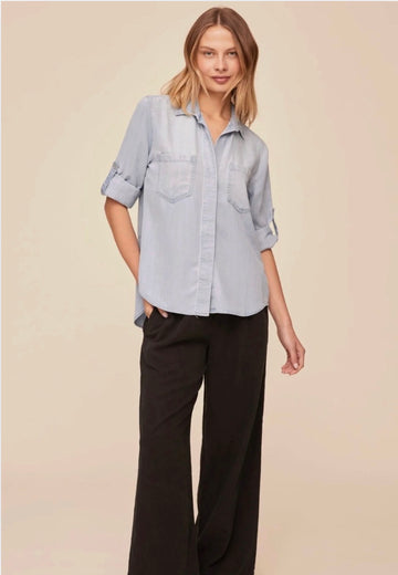 Woman wearing a light blue shirt and black pants on a beige background