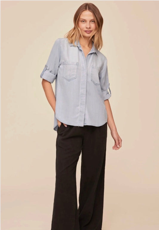 Woman wearing a light blue shirt and black pants on a beige background