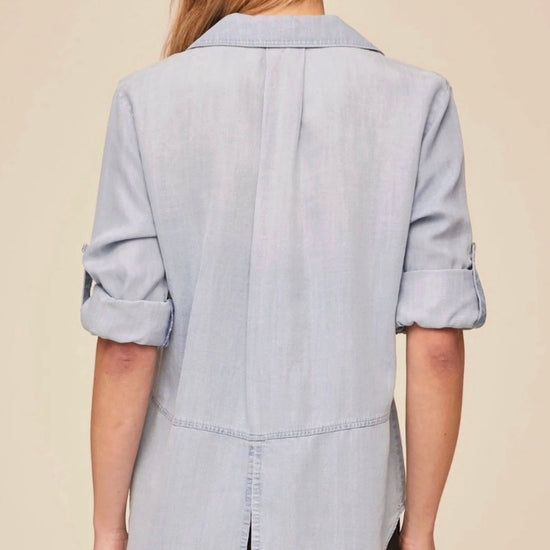 Woman wearing a light blue shirt and black pants on a beige background