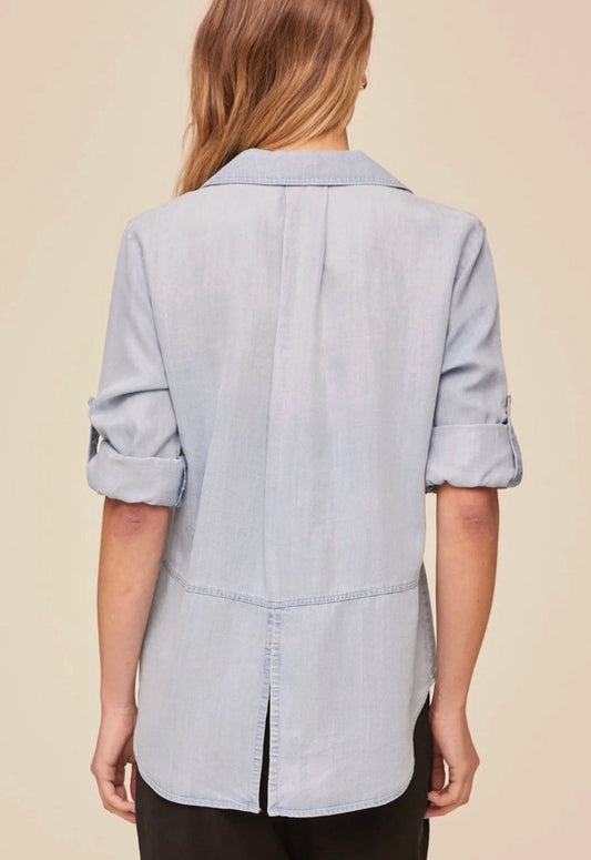 Woman wearing a light blue shirt and black pants on a beige background