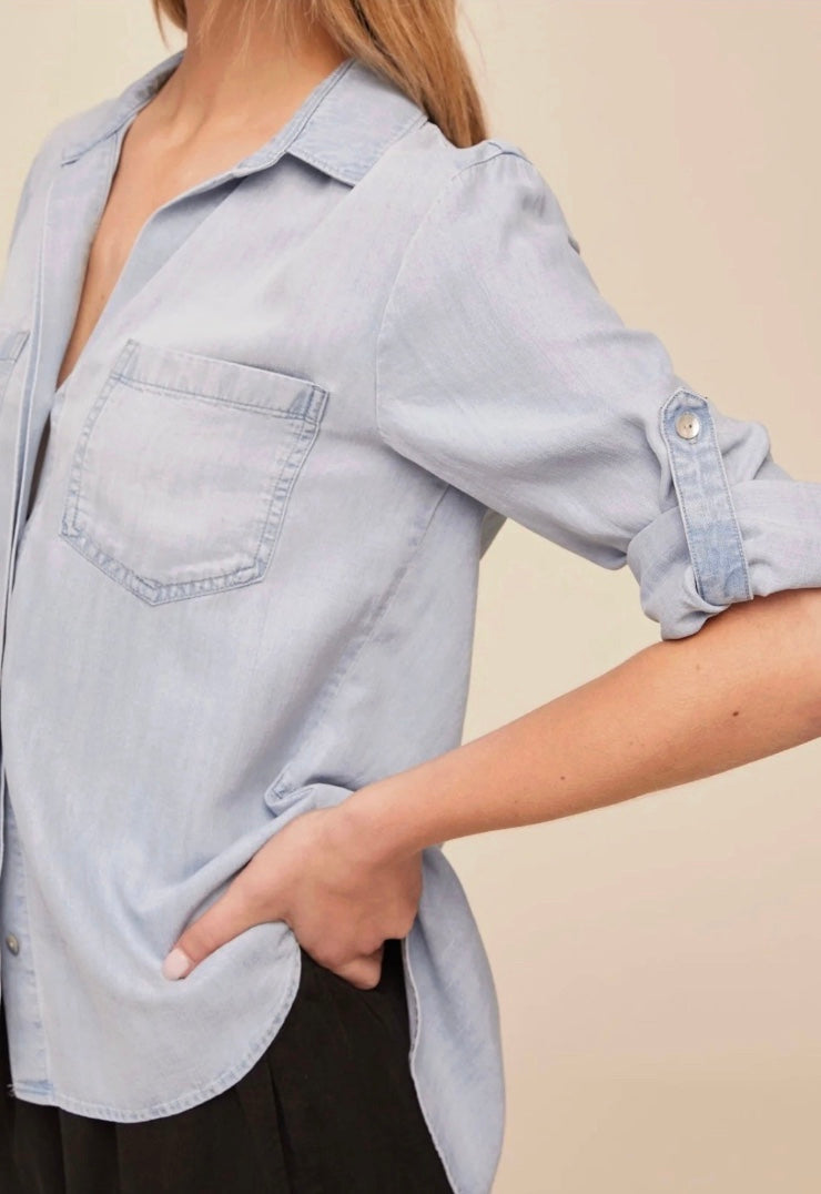 Woman wearing a light blue shirt and black pants on a beige background