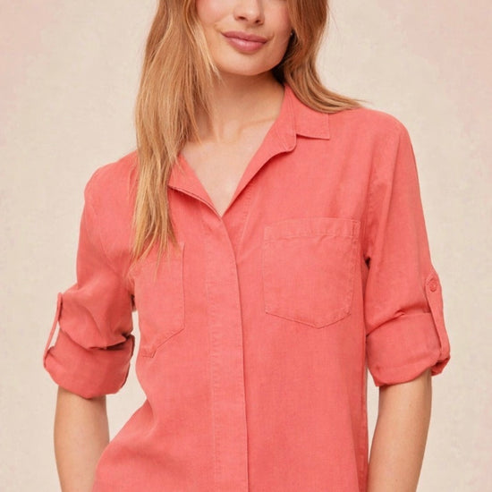 Person wearing a coral shirt with rolled-up sleeves on a beige background