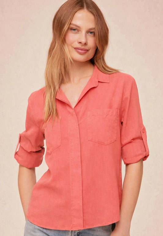 Person wearing a coral shirt with rolled-up sleeves on a beige background