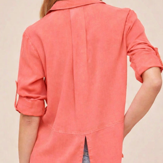 Person wearing a coral shirt with rolled-up sleeves on a beige background