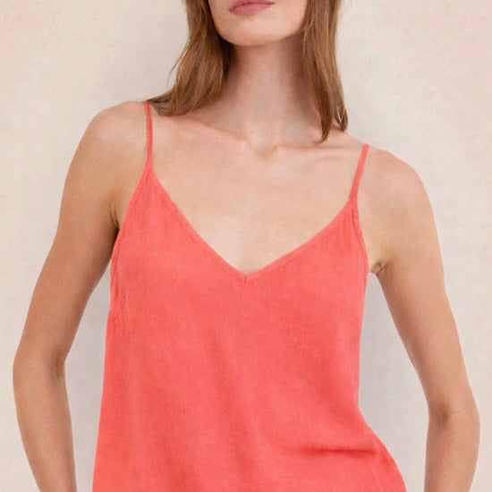 Woman wearing a coral tank top against a plain background