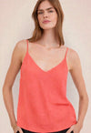 Woman wearing a coral tank top against a plain background