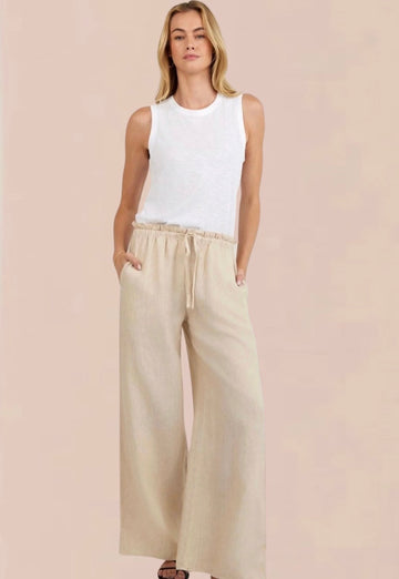 Woman wearing a white sleeveless top and beige wide-leg pants 