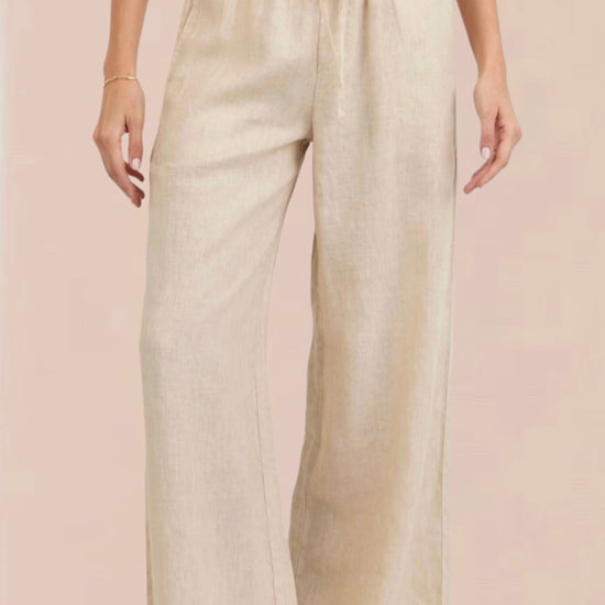 Woman wearing a white sleeveless top and beige wide-leg pants 