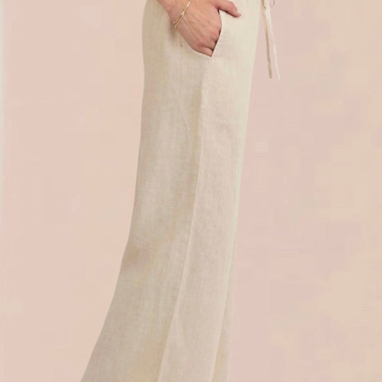 Woman wearing a white sleeveless top and beige wide-leg pants 