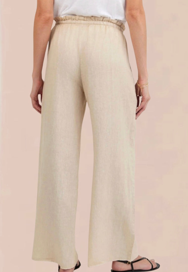 Woman wearing a white sleeveless top and beige wide-leg pants 