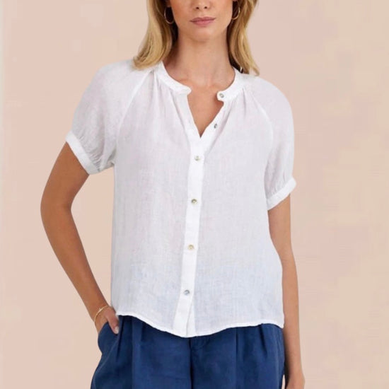 Woman wearing a white blouse and blue shorts on a beige background