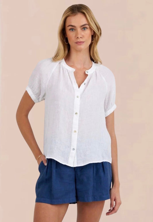 Woman wearing a white blouse and blue shorts on a beige background